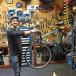 Aaron Grand standing in the bicycle service shop